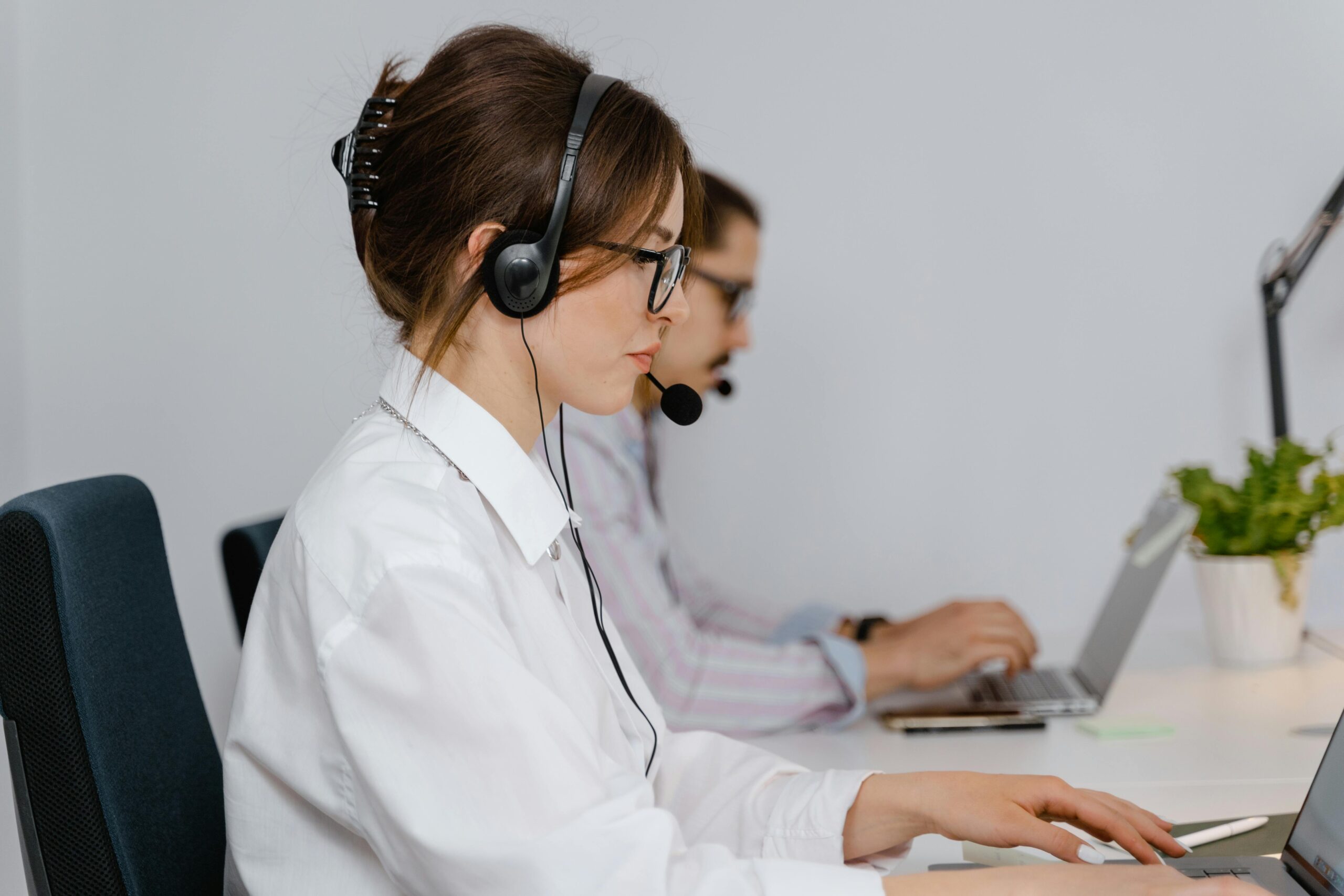 Customer service agents working at call center with headsets, focused on providing support.